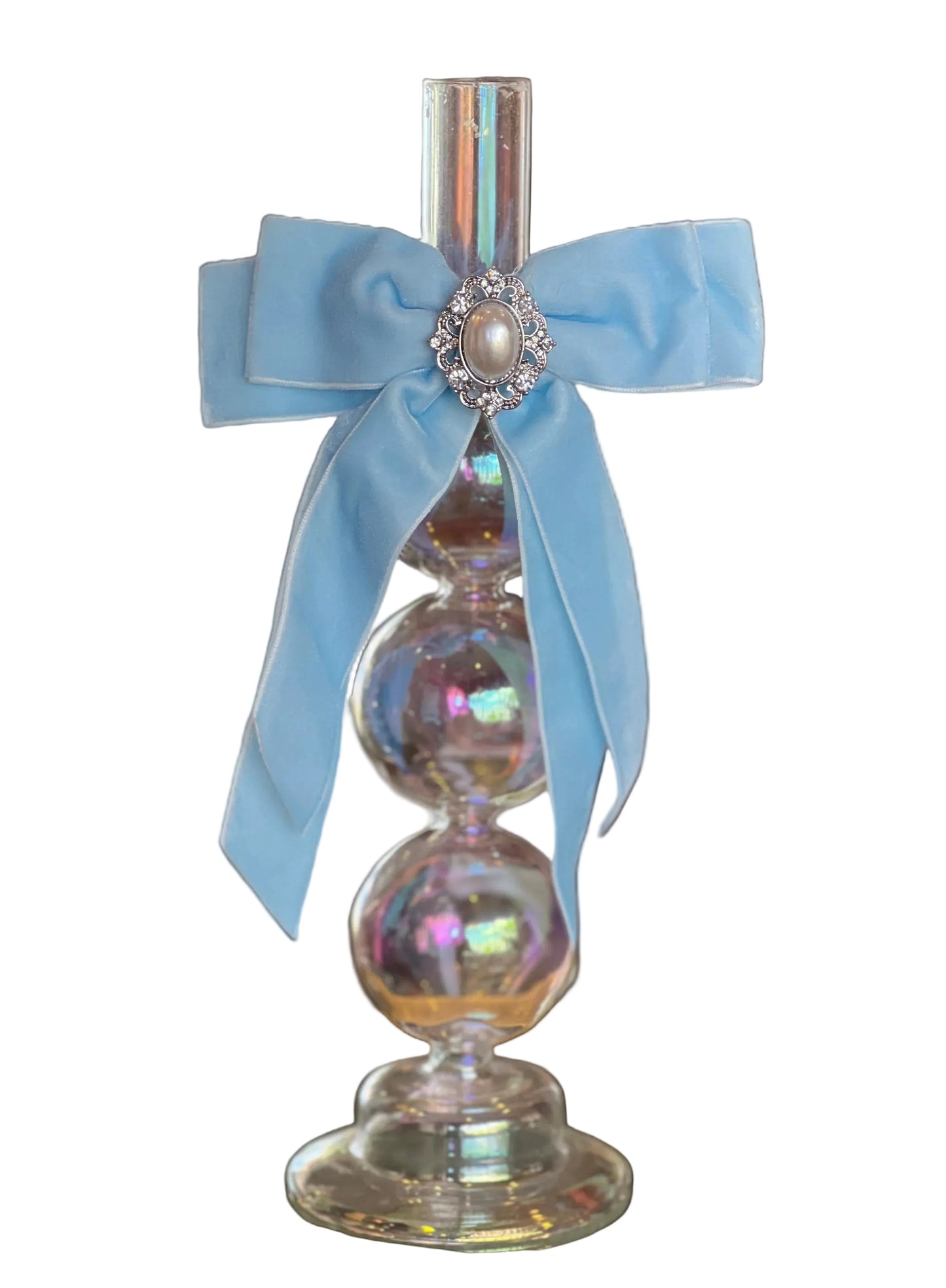 Decorative irridescent candlestick with a blue ribbon and pearl accent on a reflective surface.